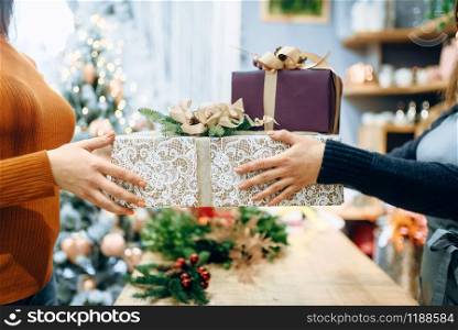 Wrapping service seller gives to customer christmas gift box. Buyer ordered a package of present, festive packing. Wrapping service seller gives to customer gift box