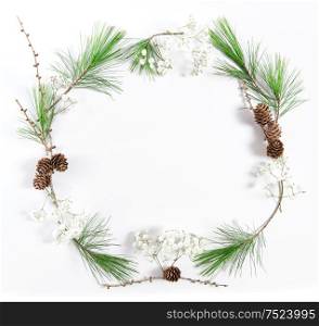 Wreath from pine tree branches with cones on white background. Christmas flat lay