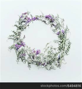 Wreath made of wild flowers on white background. Summer concept. Flat lay, top view. Floral design and purple flowers arrangement . Mouse pea. Vetch multicolor (Vicia cracca)