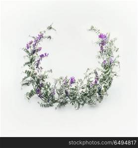 Wreath made of wild purple flowers with leaves on white background. Summer concept. Flat lay, top view. Floral design and flowers arrangement . Mouse pea. Vetch multicolor (Vicia cracca)