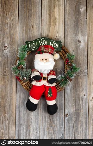 Wreath with Santa Claus symbol on rustic wood. Layout in vertical format.