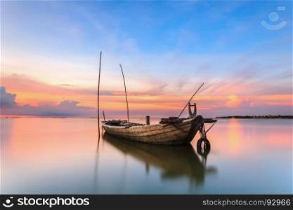 Wrecked fishing boat at sea with sunset