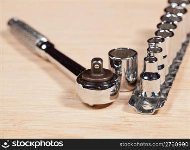 Wrench and miniature sockets in a holder on a piece of wood bench