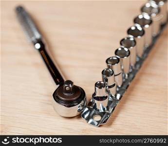 Wrench and miniature sockets in a holder on a piece of wood bench