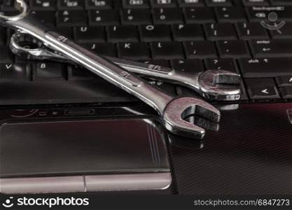 wrench tool and screwdrivers over a laptop, repair service concept