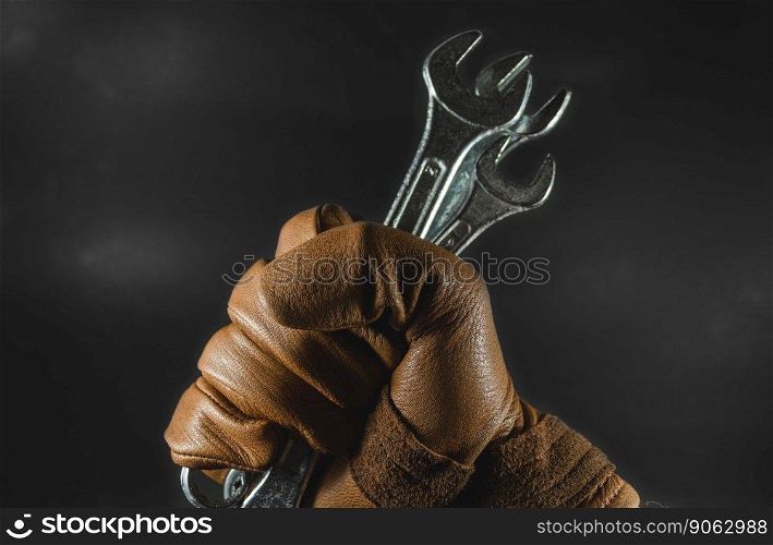 wrenchs were holding by leather glove man hand in dark light