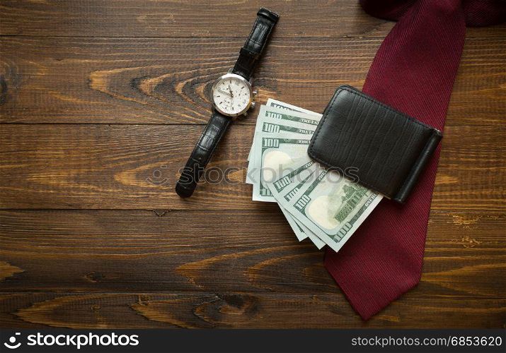 Wrist watches, money in purse and red tie on dark wooden background