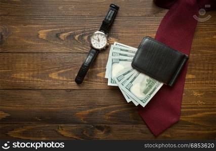 Wrist watches, money in purse and red tie on dark wooden background