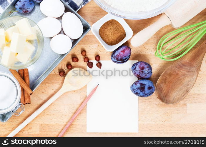 writing a recipe for plum cake. writing a recipe for plum cake with baking ingredients and tools from top with paper and a pencil