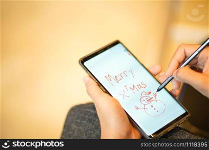Writing Christmas greetings through mobile phone technology using current people?s applications.People use phone technology to draw pictures and write greetings for families on Christmas day.