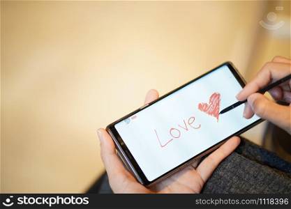 Writing heart for valentine greetings through mobile phone technology using current people?s applications.People use phone technology to draw pictures and write greetings for families on valentines day.