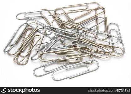 Writing metal paper clips lie in bulk on a white background of a paper