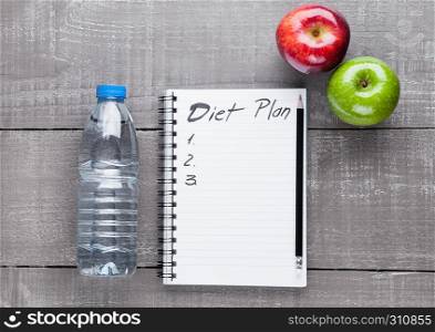Writing pad with apples and water as diet idea on wooden board