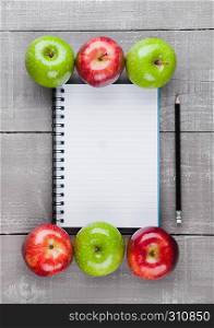 Writing pad with healthy apples as diet plan idea on wooden board