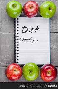 Writing pad with healthy apples as diet plan idea on wooden board