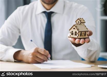 writing real estate agent holding house. High resolution photo. writing real estate agent holding house. High quality photo