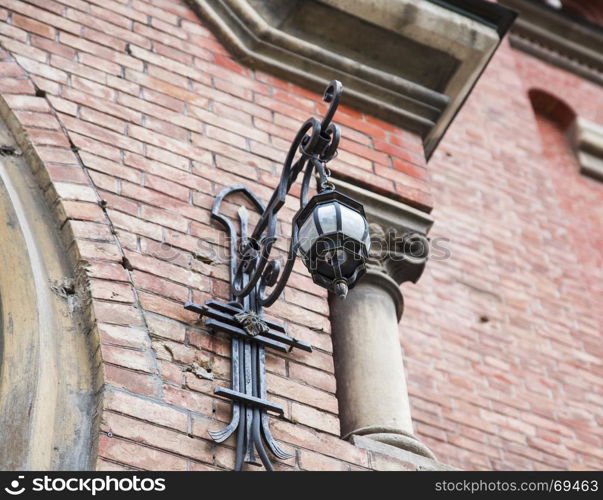wrought iron lantern hanging on the wall of a house of red brick, bottom view
