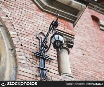 wrought iron lantern hanging on the wall of a house of red brick, bottom view