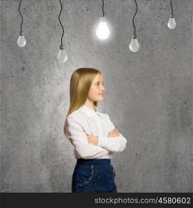 Wunderkind. Cute school girl against grey wall with bulbs hanging above