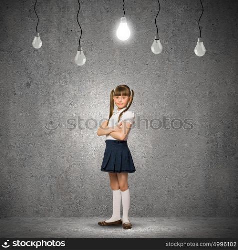 Wunderkind. Cute school girl against grey wall with bulbs hanging above