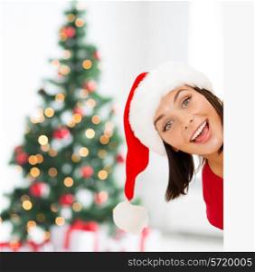 x-mas, people, advertisement and sale concept - happy woman in santa helper hat with blank white board over living room and christmas tree background