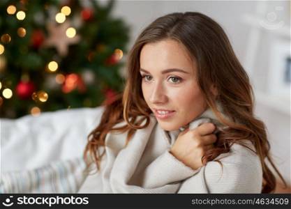 x-mas, winter holidays and people concept - happy young woman with plaid over christmas tree at home