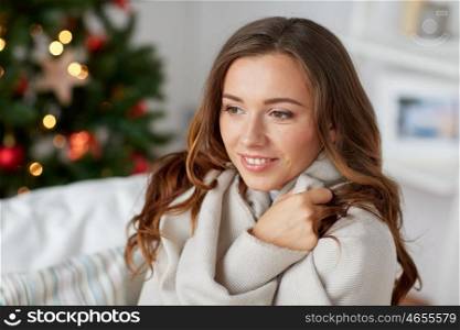 x-mas, winter holidays and people concept - happy young woman with plaid over christmas tree at home
