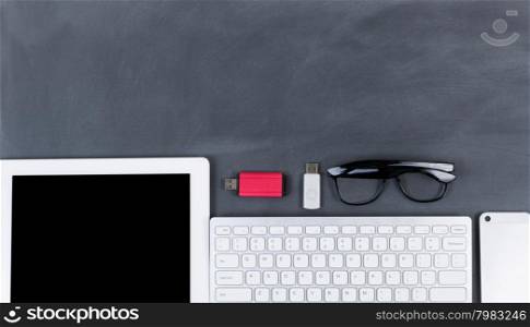 &#xA;High angled view of blackboard with computer, keyboard, cell phone and thumb drives. &#xA;