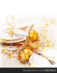 &#xA;Photo of xmas holiday table setting, closeup festive dinnerware still life, two glasses for champagne, traditional New Year alcohol beverage, luxury white plate decorated with golden bubble toy