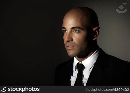 &#xA;Portrait of a man wearing black suit, white shirt and stylish tie, standing over dark background with copy space, expensive outfit, fashion and business lifestyle