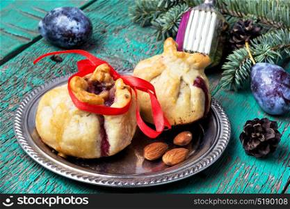 Xmas baked with plum. Christmas sweet plum buns on the background with fir-tree