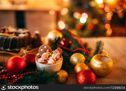 Xmas gingerbread man, holiday dessert closeup. Christmas traditional symbol, festive sweet food, fir tree branch, red balls. Xmas gingerbread man, holiday dessert closeup