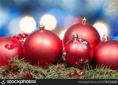 Xmas still life - red balls at green tree with blurred blue Christmas lights background