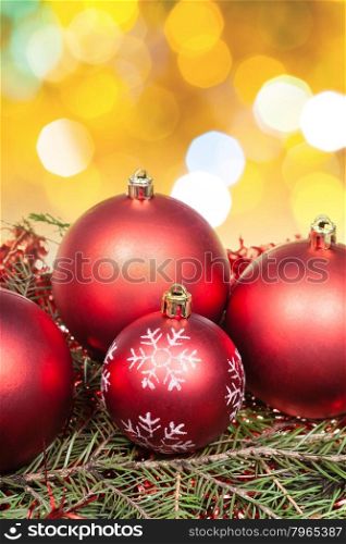 Xmas still life - red balls at green tree with blurred yellow, brown, green Christmas lights bokeh background