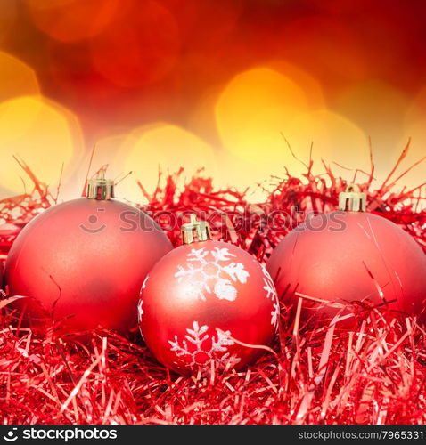 Xmas still life - red balls, tinsel with blurred red and yellow Christmas lights bokeh background