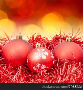 Xmas still life - red balls, tinsel with blurred red and yellow Christmas lights bokeh background