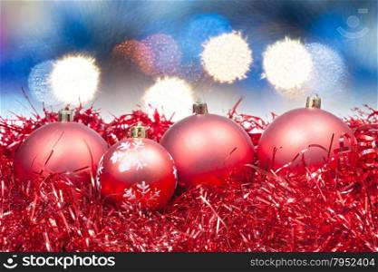 Xmas still life - red balls, tinsel with soft blue Christmas lights background