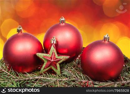 Xmas still life - red baubles, star, green tree with blurred red and yellow Christmas lights bokeh background