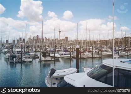 Yacht at harbour in Auckland with city skyline and Auckland Sky Tower, the iconic landmark of Auckland, New Zealand.