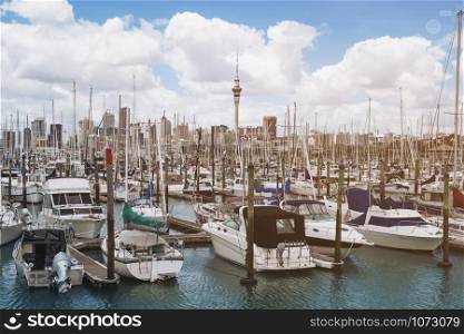 Yacht at harbour in Auckland with city skyline and Auckland Sky Tower, the iconic landmark of Auckland, New Zealand.