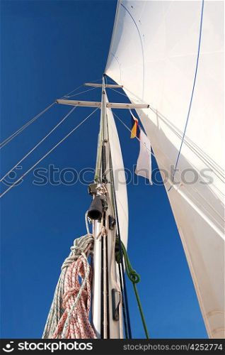 Yacht mast with ropes and sailing in blue sky