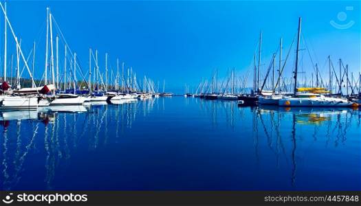 Yacht port over blue nature scene, row of luxury sailboats reflected in water