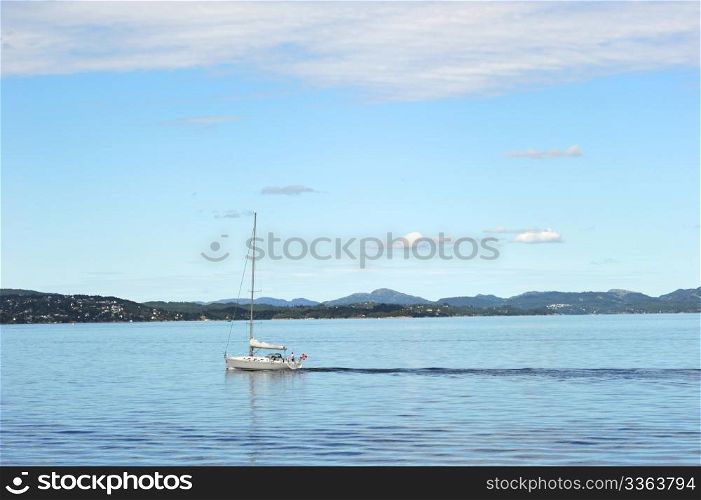 Yacht sailinng past Norway coastline near the Bergen