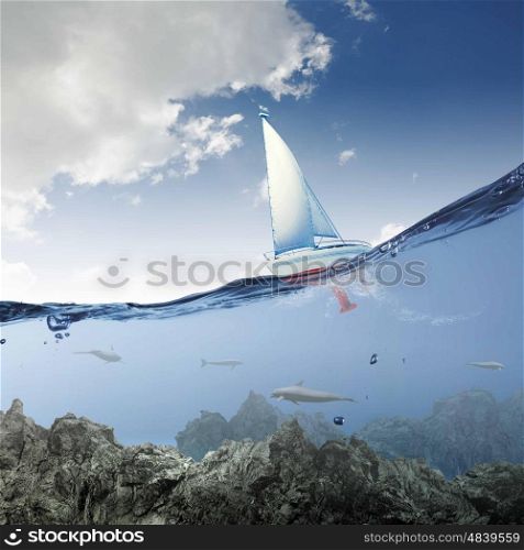 Yachting sport. Floating yacht and dolphins swimming under water