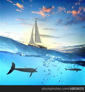 Yachting sport. Floating yacht and dolphins swimming under water