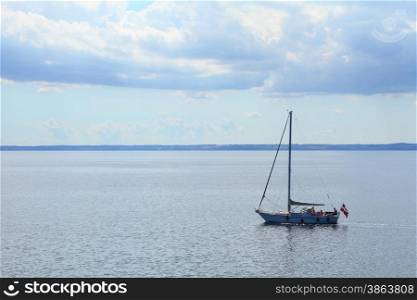 Yachting yacht sailboat sailing in baltic sea under danish flag ensign blue sky sunny day summer vacation. Tourism luxury lifestyle.