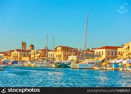 Yachts and boats in the harbour and waterfront in Aegina town at sunset, Aegina Island, Greece