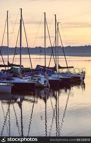 Yachts and boats moored in a harbour at sunrise. Candid people, real moments, authentic situations