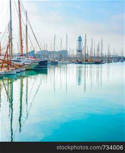 Yachts and sailboats in marina reflecting on turquoise water in sunshine day, Barcelona, Spain