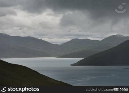 Yamdrok Lake with mountains under cloudy sky, Nagarze, Shannan, Tibet, China